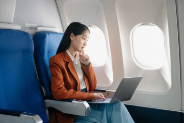 Genç Asyalı yönetici, dijital tablet, dizüstü bilgisayar ve akıllı telefondan birden fazla iş yaparak birinci sınıfta başarılı oluyor. Stil içinde seyahat et, zarafetle çalış.