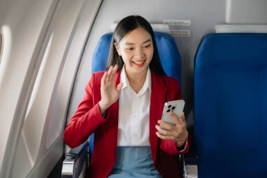 Genç Asyalı yönetici, dijital tablet, dizüstü bilgisayar ve akıllı telefondan birden fazla iş yaparak birinci sınıfta başarılı oluyor. Stil içinde seyahat et, zarafetle çalış.