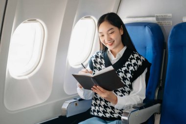 Genç Asyalı yönetici, dijital tablet, dizüstü bilgisayar ve akıllı telefondan birden fazla iş yaparak birinci sınıfta başarılı oluyor. Stil içinde seyahat et, zarafetle çalış.