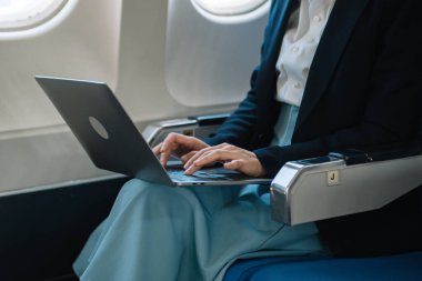 İş kadını ön tablette oturuyor, bilgisayarında mali grafikler ve istatistikler var.