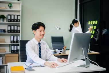 Kurumsal ve üretkenliği somutlaştıran modern ofiste takım çalışması ve iş görüşmelerine katılan iki genç Asyalı profesyonel