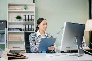 Kurumsal ve üretkenliği somutlaştıran modern ofiste takım çalışması ve iş görüşmelerine katılan iki genç Asyalı profesyonel