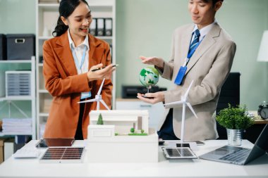 Daha yeşil bir gelecek için genç profesyoneller tarafından sürdürülebilir bir yenilik. Güneş panelleri, rüzgar türbinleri ve bir model ev ile yenilenebilir enerji çözümleri gösteriliyor. 