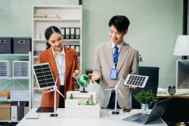 Daha yeşil bir gelecek için genç profesyoneller tarafından sürdürülebilir bir yenilik. Güneş panelleri, rüzgar türbinleri ve bir model ev ile yenilenebilir enerji çözümleri gösteriliyor. 