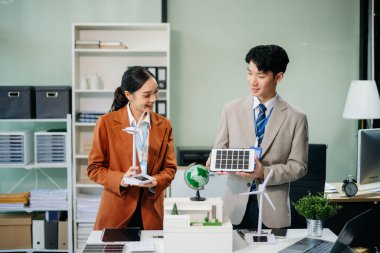 Daha yeşil bir gelecek için genç profesyoneller tarafından sürdürülebilir bir yenilik. Güneş panelleri, rüzgar türbinleri ve bir model ev ile yenilenebilir enerji çözümleri gösteriliyor. 