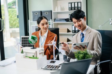 Daha yeşil bir gelecek için genç profesyoneller tarafından sürdürülebilir bir yenilik. Güneş panelleri, rüzgar türbinleri ve bir model ev ile yenilenebilir enerji çözümleri gösteriliyor. 