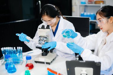 Asyalı kadın bilim adamları modern laboratuarda kimya araştırması yapıyorlar.