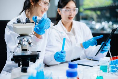 Asyalı kadın bilim adamları modern laboratuarda kimya araştırması yapıyorlar.