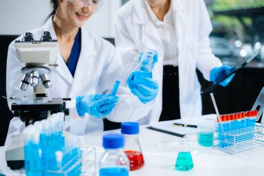 Asyalı kadın bilim adamları modern laboratuarda kimya araştırması yapıyorlar.