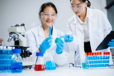 Asyalı kadın bilim adamları modern laboratuarda kimya araştırması yapıyorlar.