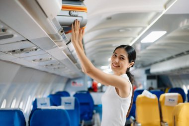 Çekici Asyalı kadın uçak yolcusu dizüstü bilgisayar ve tabletle kablosuz bağlantı kullanarak rahat koltukta oturuyor. Stil içinde seyahat et, zarafetle çalış..