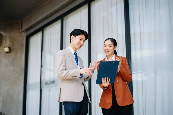 Businesswoman and man going in city center in smart casual business style, talking, working together, stylish freelance people, holding coffee and laptop,tablet and smartphone discussin