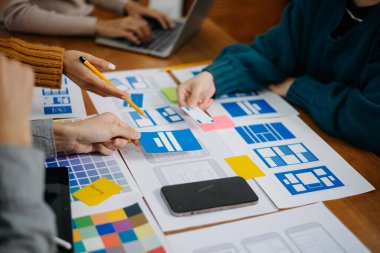  UX geliştiricisi ve ui tasarımcısı modern ofiste müşteri breif ve renk kodu ile mobil uygulama arayüzü kablo tasarımı hakkında beyin fırtınası yapıyorlar