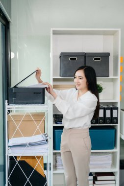 Asyalı iş kadını elinde kalem tutarken aynaya yapıştırdığı not kağıdına hatırlatma bilgisayarı ve masadaki tablet olarak not alıyor.