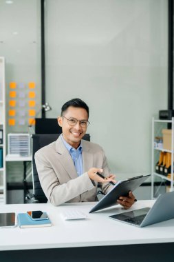  Masaya dizüstü bilgisayar ve tablet yerleştiren Asyalı işadamı 