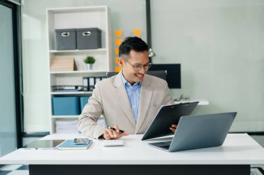  Masaya dizüstü bilgisayar ve tablet yerleştiren Asyalı işadamı 