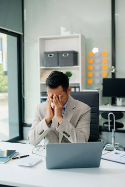 Hüsrana uğramış genç işadamı çalıştığı yerde dizüstü bilgisayarla çalışıyor.