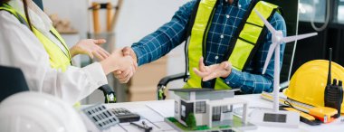 business people having consultation about wind energy at company office. on architectural project site and making model house. Asian industry professional 