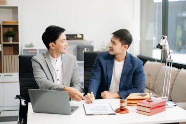 Asyalı iş adamları ve avukatlar masada oturan sözleşme belgelerini tartışıyorlar. Hukuk kavramları, tavsiyeler, hukuk hizmetleri. Sabah aydınlığında.