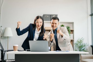 Ofiste yeni bir proje üzerinde çalışırken mutlu iş adamları. Ofiste bir dizüstü bilgisayar ve tablet kullanan çeşitli iş adamları.