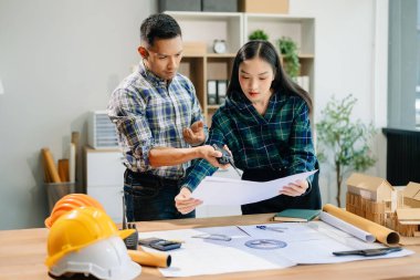 Modern ofisteki inşaat sahasında mimari projeyle büyük çizimlere yansıyan yaratıcı mimar