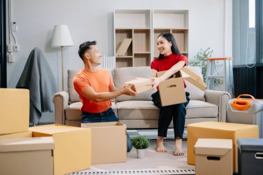 Asyalı genç ve çekici bir çift, yeni evlerinde tablet ve akıllı telefon, alışveriş mobilyaları, karton paketlerle dekore edilmiş evler kullanıyor. Genç evli Asyalı eve taşınıyor..