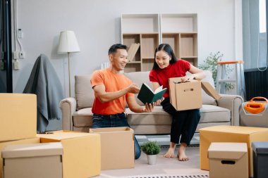 Asyalı genç ve çekici bir çift, yeni evlerinde tablet ve akıllı telefon, alışveriş mobilyaları, karton paketlerle dekore edilmiş evler kullanıyor. Genç evli Asyalı eve taşınıyor..