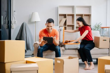 Asya 'lı genç çift kanepede oturup oyun kumandası kullanıyor. Oturma odasındaki kanepede birlikte eğleniyorlar. Asyalı evli çift ailesi