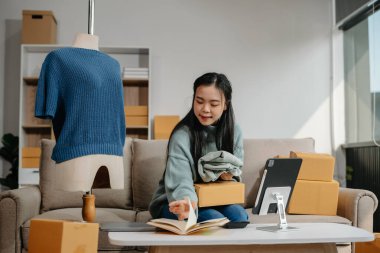 Güzel Asyalı kadın blogcu, video kaydına kamera önünde kıyafetlerini gösteriyor. 