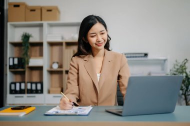 Ofisteki beyaz masada otururken tablet ve dizüstü bilgisayarda yazan güzel bir kadın.
