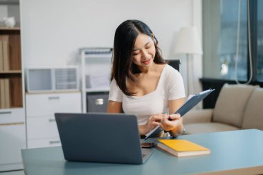 Ofisteki beyaz masada otururken tablet ve dizüstü bilgisayarda yazan güzel bir kadın.