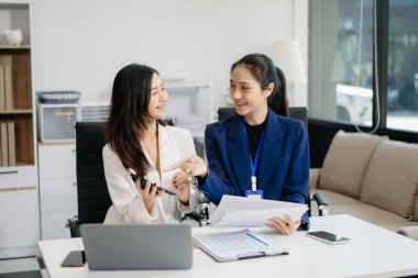 İş kadınları çalışır ve iş planlarını tartışırlar. Bir insan çalışanı meslektaşına modern ofisteki sonuçları açıklar ve gösterir..