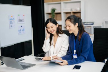 Bayan meslektaşımla yeni projeyi tartışıyoruz. Genç kadınlar modern ofiste genç Asyalı bir adamla konuşuyorlar..