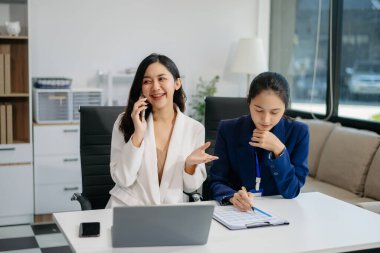 Bayan meslektaşımla yeni projeyi tartışıyoruz. Genç kadınlar modern ofiste genç Asyalı bir adamla konuşuyorlar..