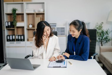 Bayan meslektaşımla yeni projeyi tartışıyoruz. Genç kadınlar modern ofiste genç Asyalı bir adamla konuşuyorlar..