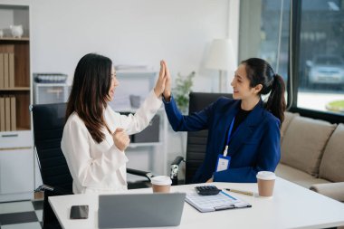 Bayan meslektaşımla yeni projeyi tartışıyoruz. Genç kadınlar modern ofiste genç Asyalı bir adamla konuşuyorlar..