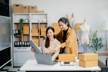 Starting small businesses SME owners, two check online orders Selling products working with boxs freelance work at home office using tablet and laptop  marketing, packaging, concept