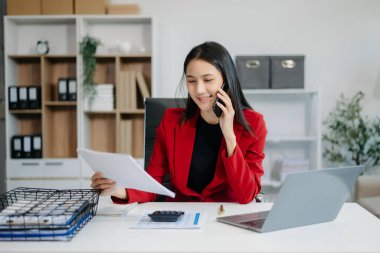 Ofisteki beyaz masada otururken tablet ve dizüstü bilgisayarda yazan güzel bir kadın.