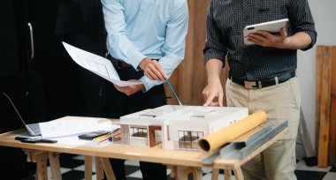 Çalışma ve tablet hakkında konuşan iki meslektaşım, ofisteki inşaat alanında mimari projeli dizüstü bilgisayar.