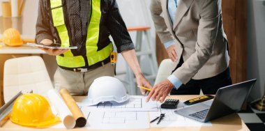 Professional collaboration in architecture. Two engineers work on construction plans, using tools like laptops, tablets, and scale models. Perfect for depicting teamwork 