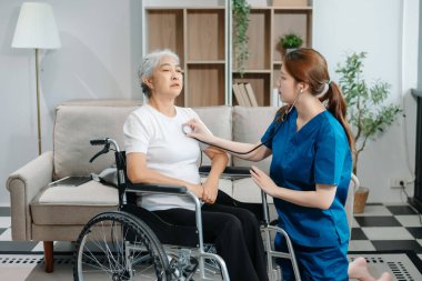 Asyalı bakıcı doktor yaşlı hasta kadın terapisti muayene ediyor. Huzurevinde yaşlı yaşlı bir kadınla ilgileniyor. Hastane konsepti üzerine oturuyor. Yardım etmek ve teşvik etmek