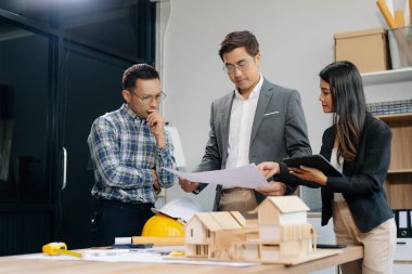 Birlikte çalışan mühendis ekipleri, mimari proje sahasında çalışan miğferler takıyor ve model ev yapıyorlar. Asya endüstrisi profesyonel takımı görevde.