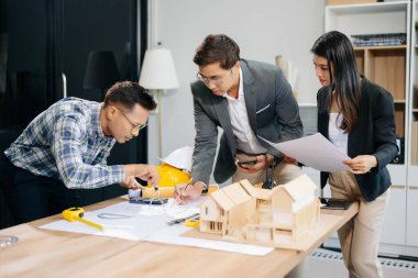 Birlikte çalışan mühendis ekipleri, mimari proje sahasında çalışan miğferler takıyor ve model ev yapıyorlar. Asya endüstrisi profesyonel takımı görevde.