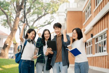 Genç Asyalı üniversite öğrencileri ve bir kız öğrenci grubu sabahları arkadaşlarıyla kampüs parkında çalışıyor. Eğitim kavramı 