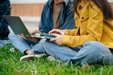 Genç Asyalı üniversite öğrencileri ve bir kız öğrenci grubu sabahları arkadaşlarıyla kampüs parkında çalışıyor. Eğitim kavramı 