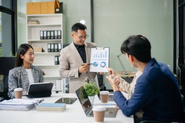 Modern bir ofiste Asyalı profesyoneller arasındaki takım çalışması ve işbirliği, kurumsal kültür, yenilik ve verimliliği gözler önüne seriyor