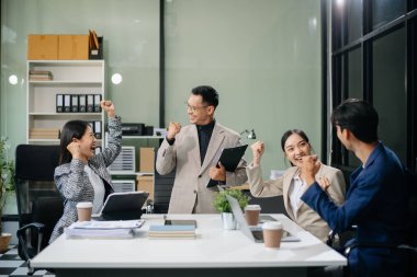 Modern bir ofiste Asyalı profesyoneller arasındaki takım çalışması ve işbirliği, kurumsal kültür, yenilik ve verimliliği gözler önüne seriyor