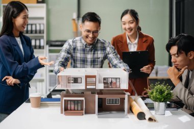 Asyalı mimarlar ve tasarımcılar modern bir ofiste beyin fırtınası yapıyor ve işbirliği yapıyor, modellerden faydalanıyor ve yenilikçi kentsel yapılar tasarlama planları yapıyorlar.