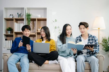 Bir grup genç Asyalı üniversite öğrencisi, dizüstü bilgisayar ve tablet kullanarak onun proje ödevi üzerinde çalışıyorlar. Birlikte, konuşmanın ve evde atıştırmanın tadını çıkarın.
