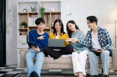 Bir grup genç Asyalı üniversite öğrencisi, dizüstü bilgisayar ve tablet kullanarak onun proje ödevi üzerinde çalışıyorlar. Birlikte, konuşmanın ve evde atıştırmanın tadını çıkarın.